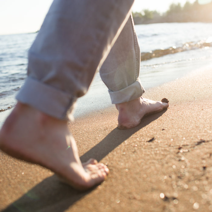 Person walking on the beach illustrating the concept of grounding (otherwise called earthing)